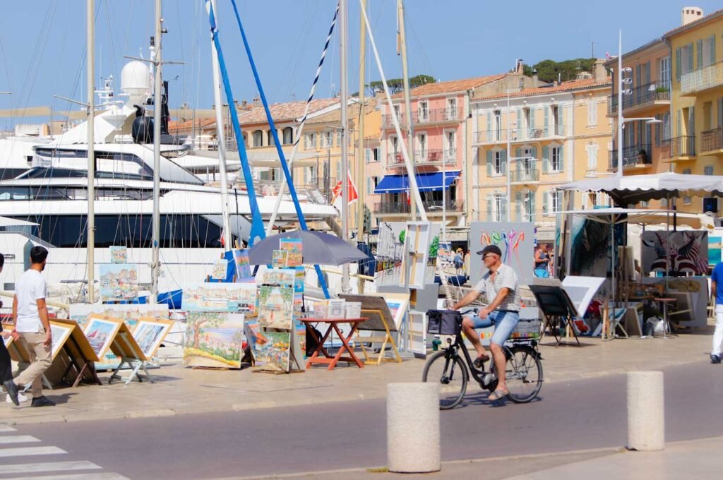 Ein Radfahrer betrachtet die ausgestellten Gemälde am Hafen von Saint-Tropez
