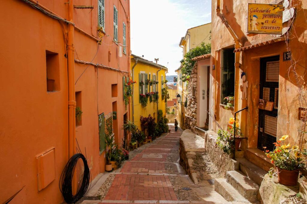 Geschwungene Gasse mit roten und gelben Häusern in Menton, Frankreich