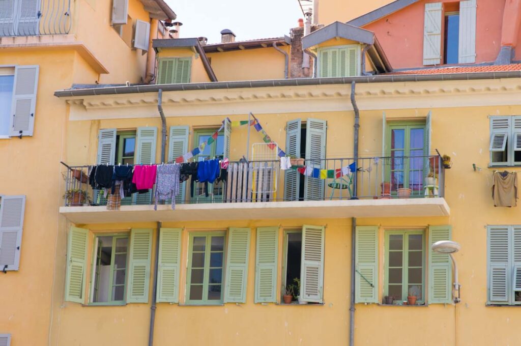 Wäsche und Girlanden auf Balkon vor gelber Fassade