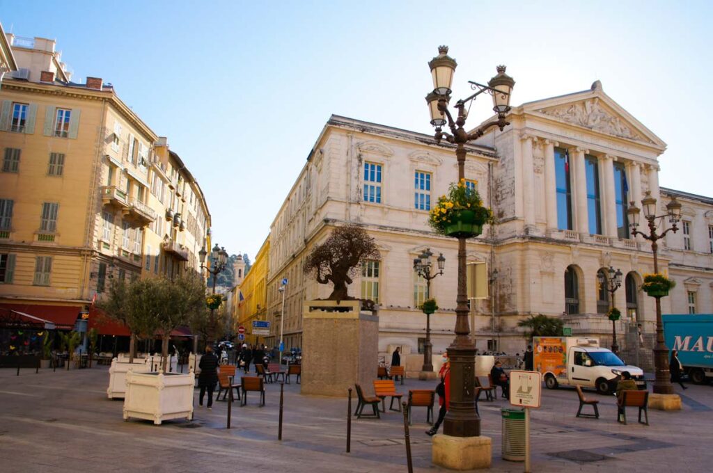 Platz mit Olivenbäumen, Straßenlaterne und Gerichtsgebäude im Hintergrund